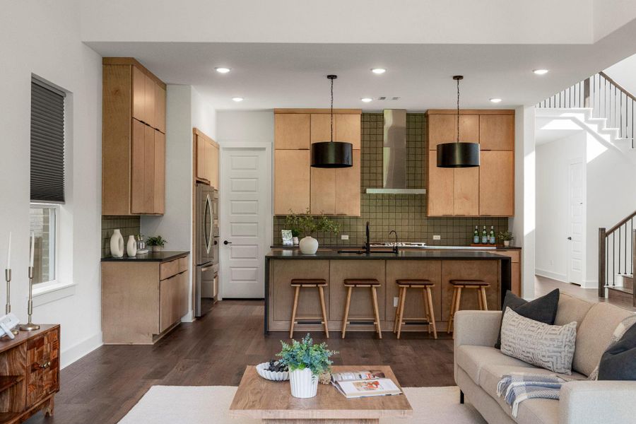 A contemporary kitchen and living area feature a spacious island, rich hardwood flooring, and seamless open-concept flow.