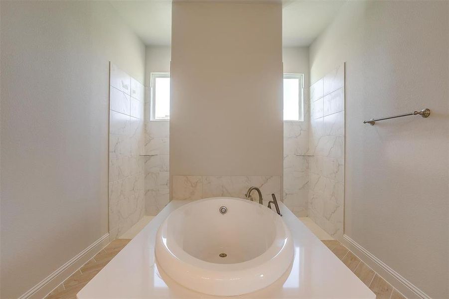 Bathroom featuring a bathing tub, tile patterned floors, and a healthy amount of sunlight