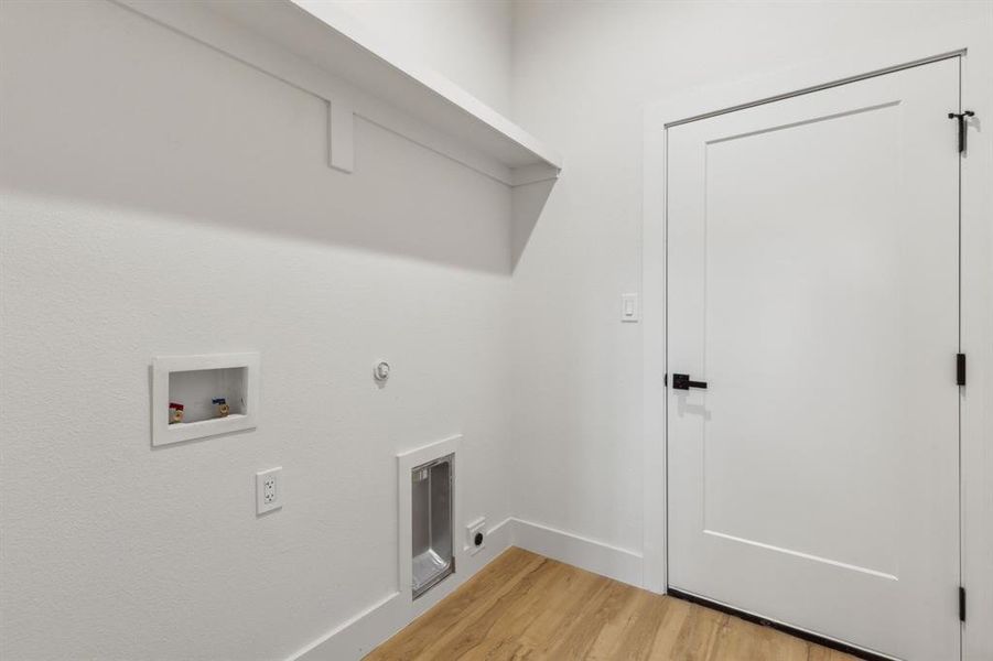 Clothes washing area with washer hookup and light wood-type flooring