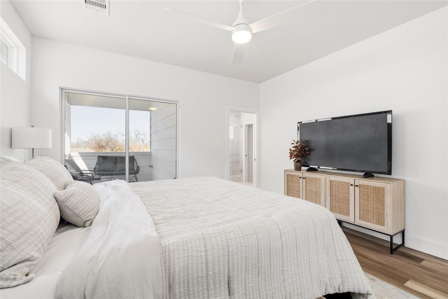 Primary suite with direct access to a covered balcony and a glimpse into the ensuite bath.