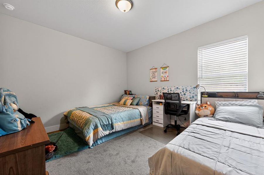 This room features light grey walls and grey carpet, with a window providing natural light