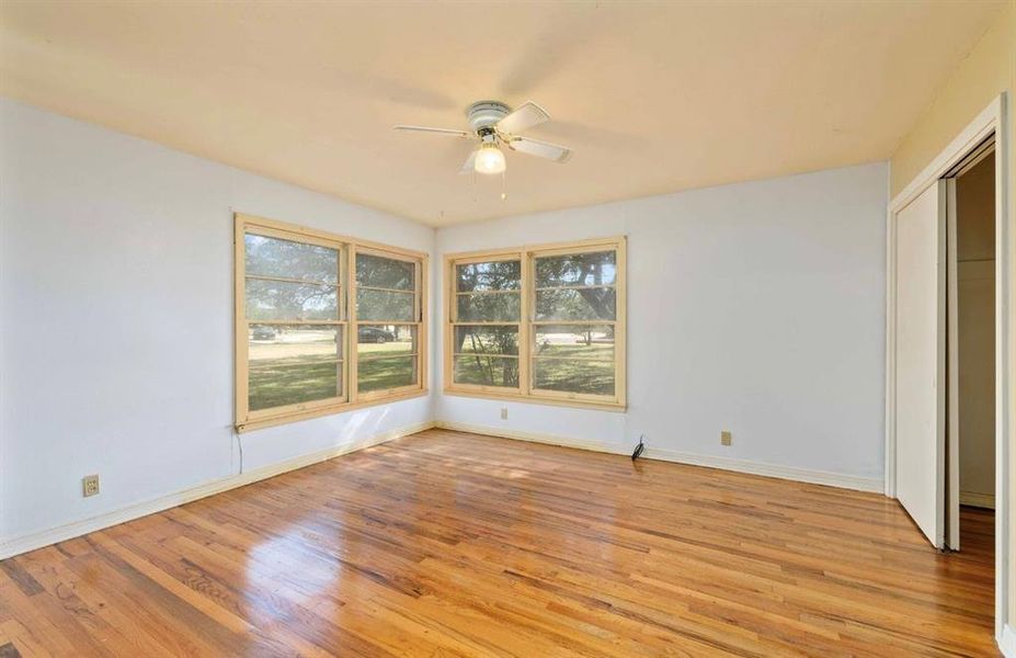 Unfurnished bedroom featuring multiple windows, light wood-type flooring, a closet, and a ceiling fan