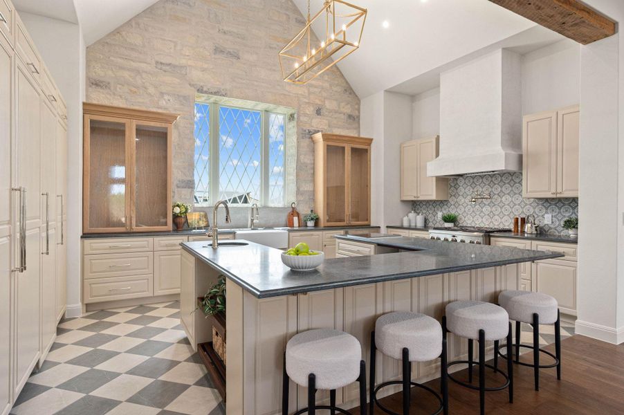 Kitchen featuring hanging light fixtures, a kitchen breakfast bar, cream cabinets, high vaulted ceiling, and dark stone countertops