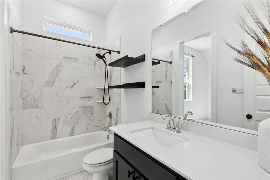 Full bathroom featuring tiled shower / bath, vanity, and toilet