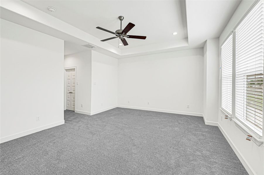 This spacious room features fresh gray carpeting, bright white walls, and a modern ceiling fan. Large windows allow ample natural light, and a door leads to an adjoining space, adding convenience and versatility. This spacious room features fresh gray carpeting, bright white walls, and a modern ceiling fan. Large windows allow ample natural light, and a door leads to an adjoining space, adding convenience and versatility.