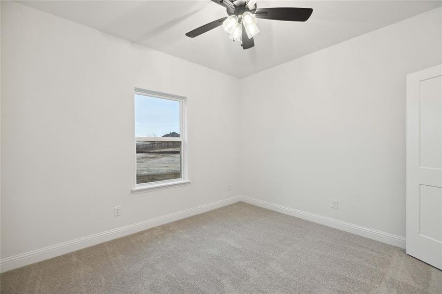 Carpeted spare room featuring ceiling fan