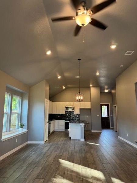 Kitchen with a center island, white cabinetry, decorative light fixtures, backsplash, and ceiling fan