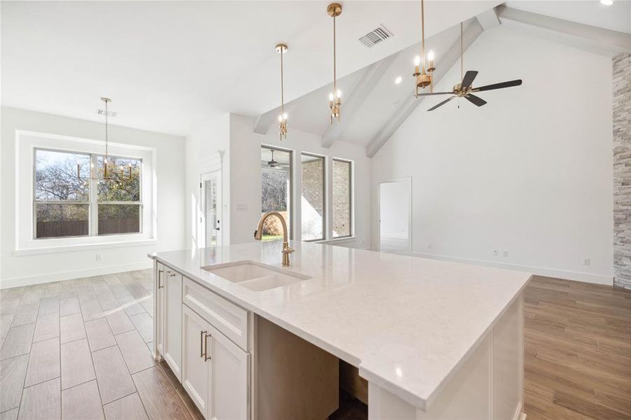 Kitchen featuring a kitchen island with sink, sink, white cabinets, and a healthy amount of sunlight