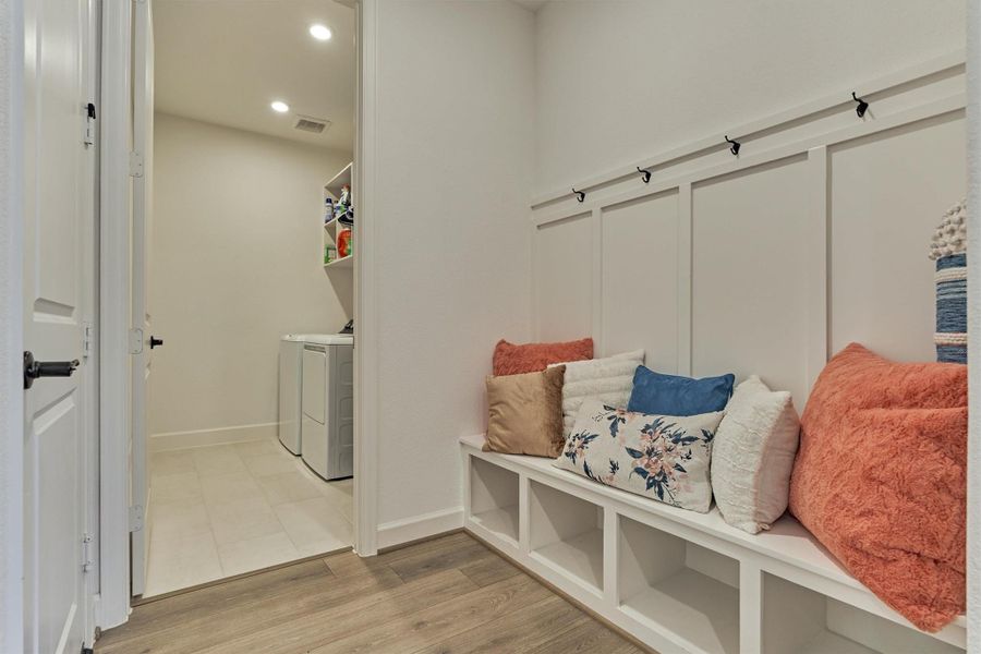 This stylish mudroom and laundry combo features sleek flooring, a cozy bench with storage, and a bright, efficient laundry area for ultimate convenience and organization.