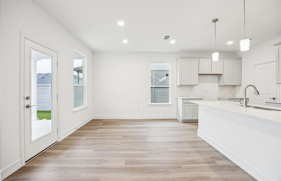 Open kitchen with adjoining nook featuring large windows and direct access to the backyard Open kitchen with adjoining nook featuring large windows and direct access to the backyard