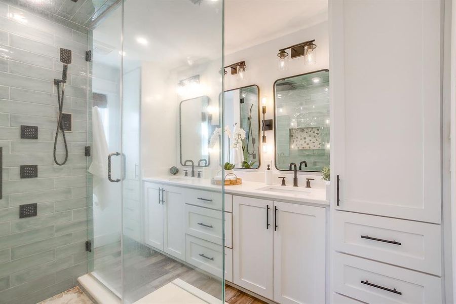 Full bathroom featuring double vanity and a stall shower