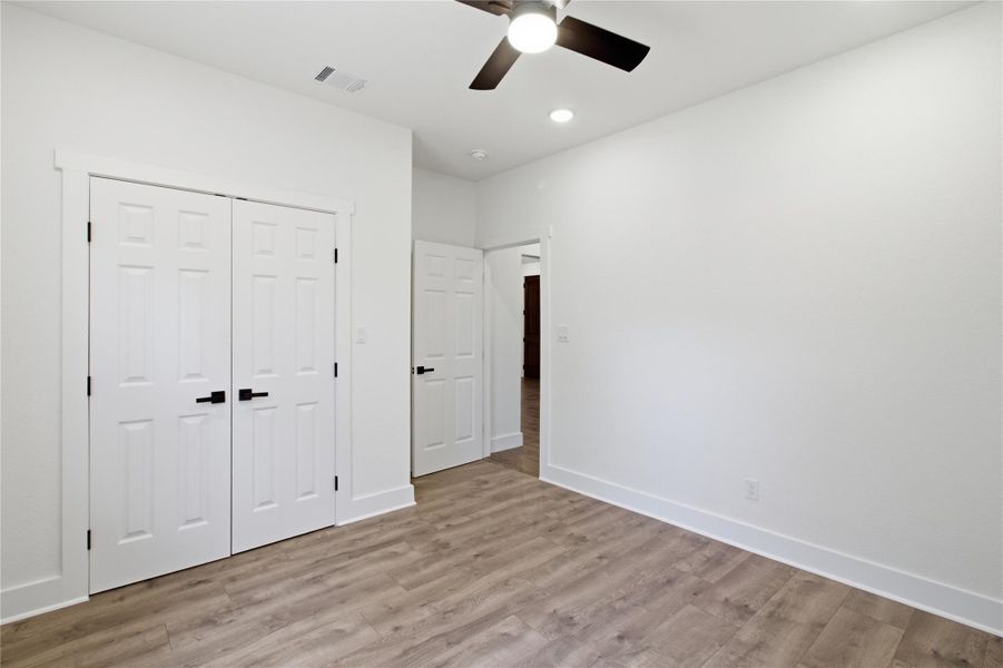 Bright and airy, this bedroom features modern plank flooring, a contemporary ceiling fan, and ample closet space. Bright and airy, this bedroom features modern plank flooring, a contemporary ceiling fan, and ample closet space.