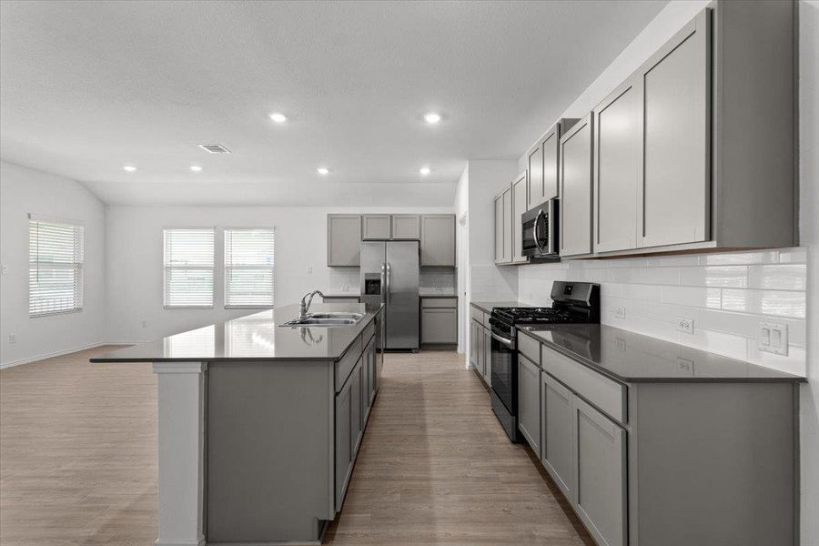 Modern kitchen with gray cabinetry, dark countertops, and stainless steel appliances, seamlessly connecting to an open living area. Modern kitchen with gray cabinetry, dark countertops, and stainless steel appliances, seamlessly connecting to an open living area.