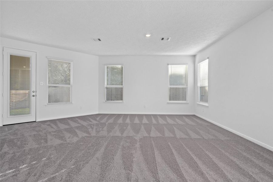 Flooded with natural light from large windows and a patio door, the Great Room feels bright and airy. Recessed lighting adds to the welcoming atmosphere, perfect for gathering with family and guests.