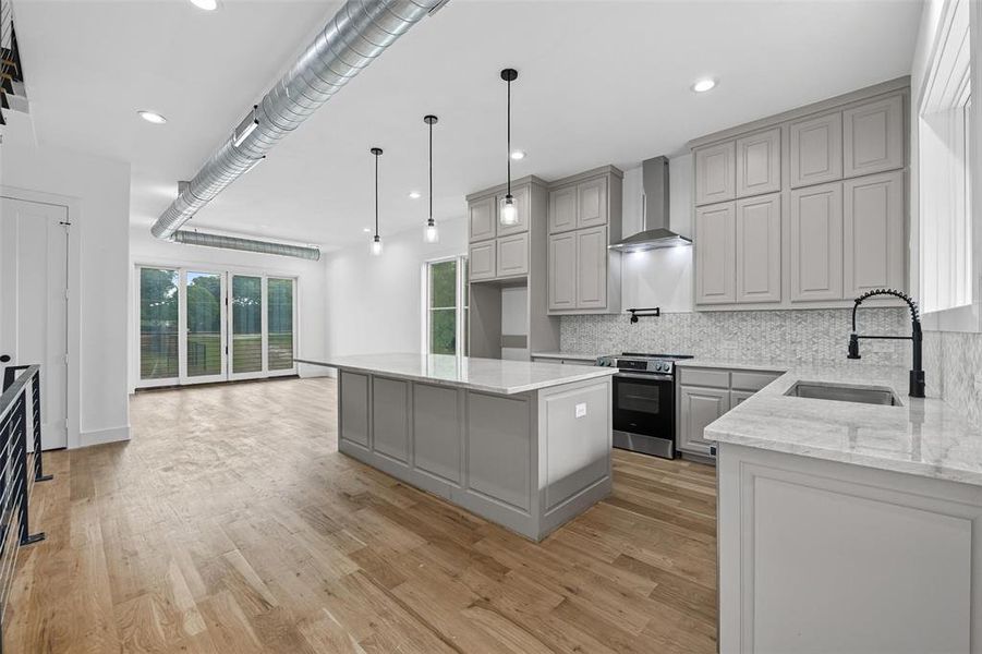 Kitchen with gray cabinets, a kitchen island, light stone countertops, stainless steel range with electric cooktop, and recessed lighting
