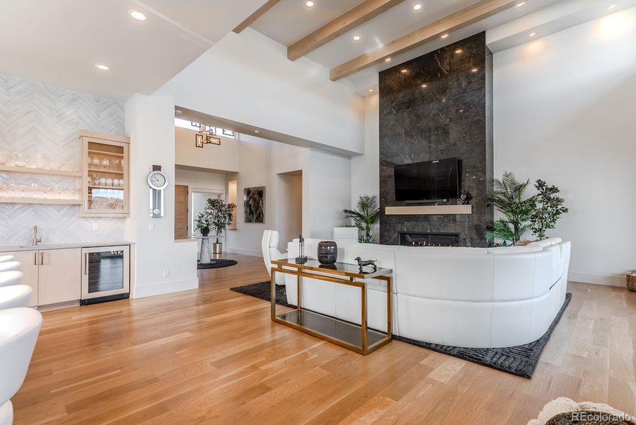 The linear fireplace—framed in large platform tile—anchors the room with sculptural contrast against pristine white walls.