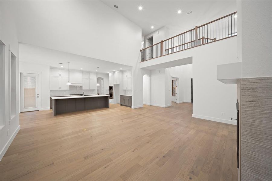 Unfurnished living room with recessed lighting, light wood-type flooring, and a towering ceiling