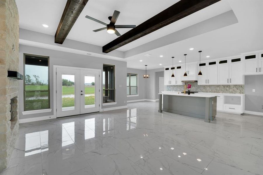 Kitchen featuring white cabinetry, a kitchen island with sink, light tile patterned flooring, decorative light fixtures, and beamed ceiling