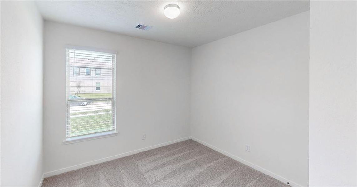 Secondary bedroom features plush carpet, custom paint and a large window.