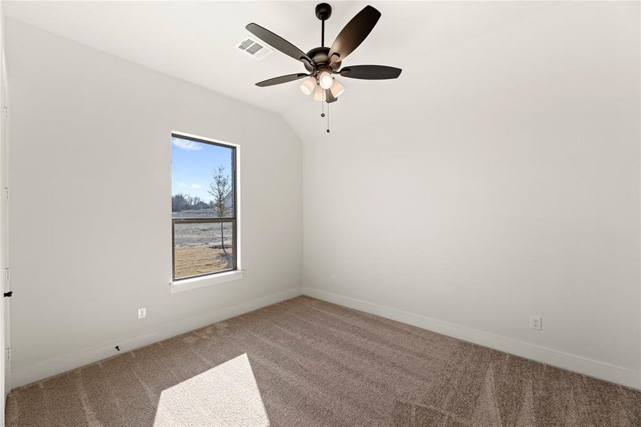 Empty room featuring vaulted ceiling, carpet, and ceiling fan