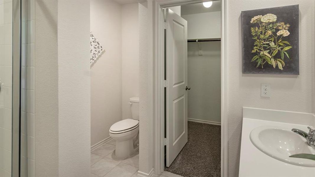 Bathroom featuring a spacious closet, vanity, light tile patterned flooring, a textured wall, and a shower
