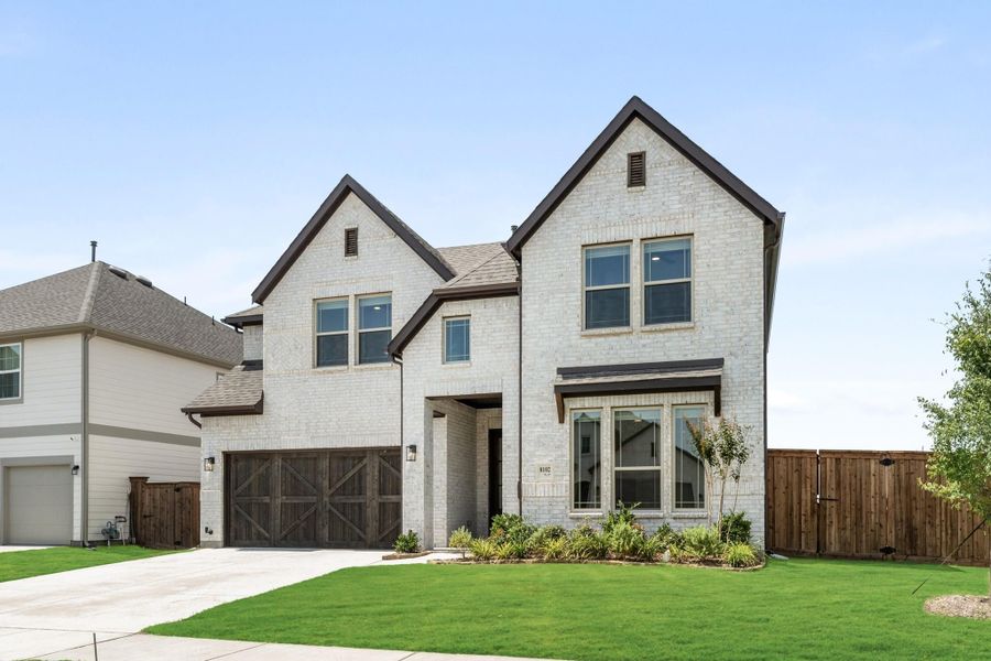 Two-story home with white brick exterior, two-car garage, and manicured front lawn Two-story home with white brick exterior, two-car garage, and manicured front lawn