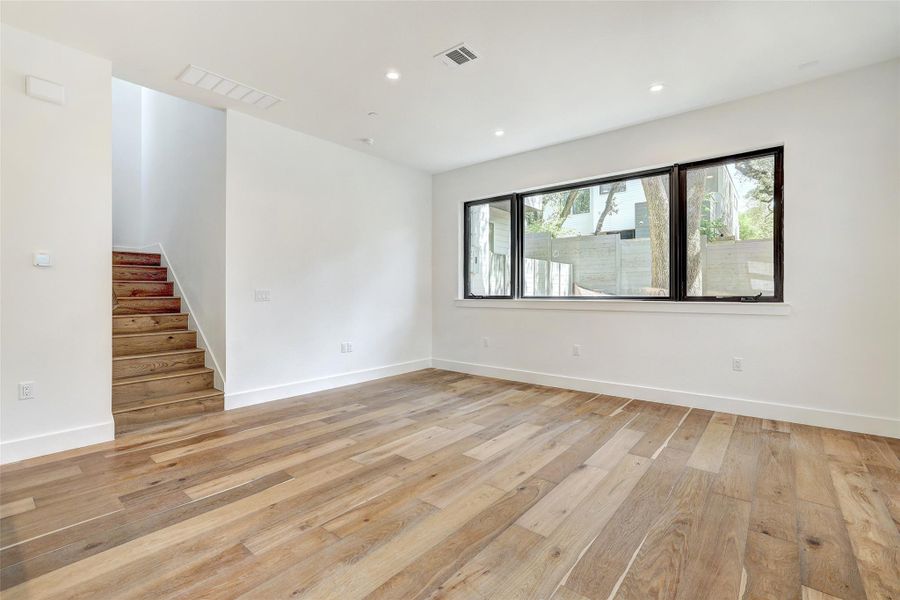 Unfurnished room featuring light wood-style floors, stairs, baseboards, and recessed lighting