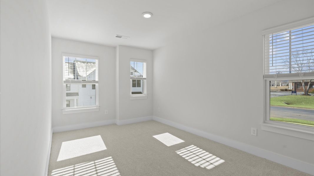 Notable bedroom offering soft carpet, a walk-in closet, and expansive windows overlooking the yard