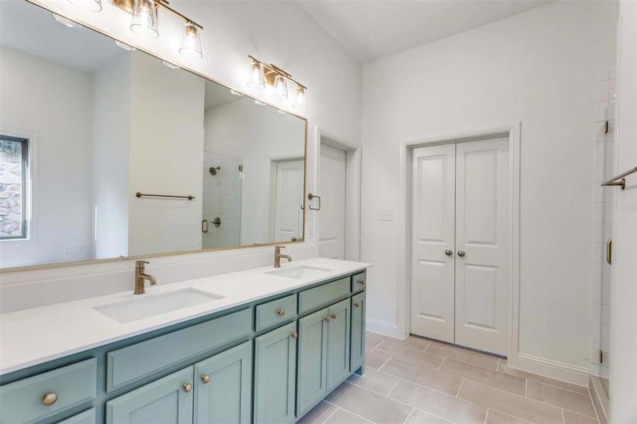 Bathroom with an enclosed shower, vanity, and tile patterned flooring