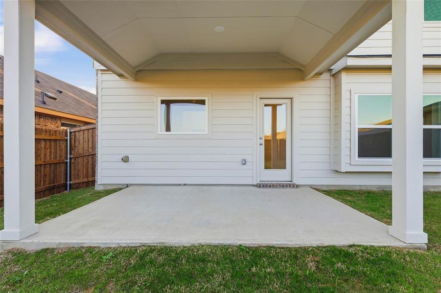 Covered concrete patio extending from the home's exterior, featuring a glass-paned door and multiple windows Covered concrete patio extending from the home's exterior, featuring a glass-paned door and multiple windows