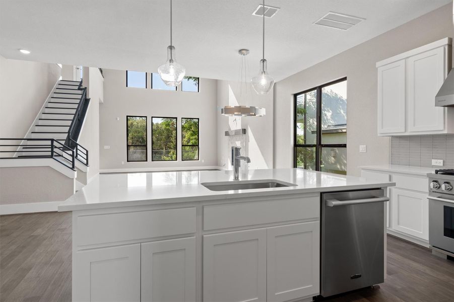 A well-lit kitchen with a spacious island, contemporary pendant lights, and large windows offering scenic outdoor views. A well-lit kitchen with a spacious island, contemporary pendant lights, and large windows offering scenic outdoor views.