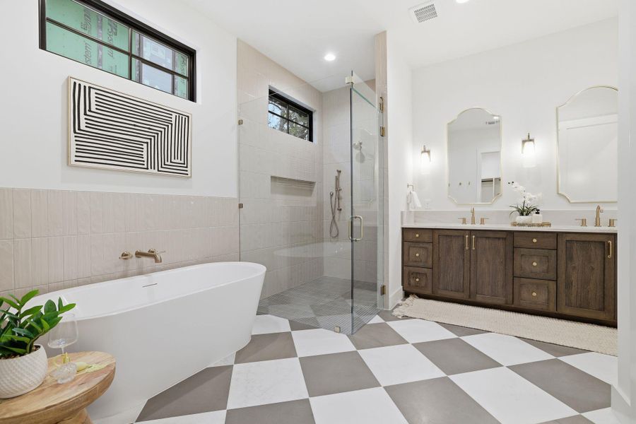Bathroom featuring a freestanding tub, double vanity, a stall shower, and light flooring