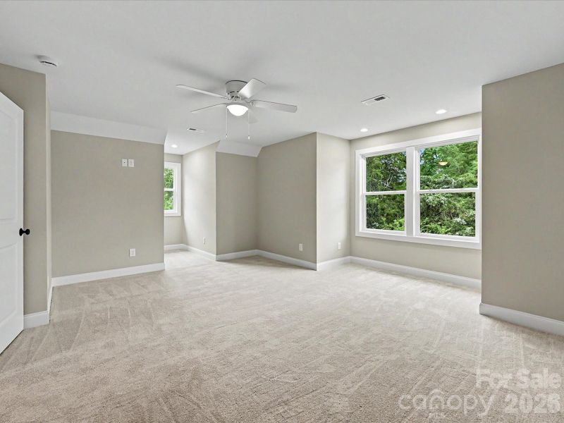 Spacious secondary bedroom on upper level offers plush carpeting, abundant natural light, and flexible space for guests, hobbies, or a home office.