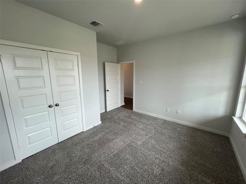 A well-proportioned bedroom with new gray carpeting awaits personalization.