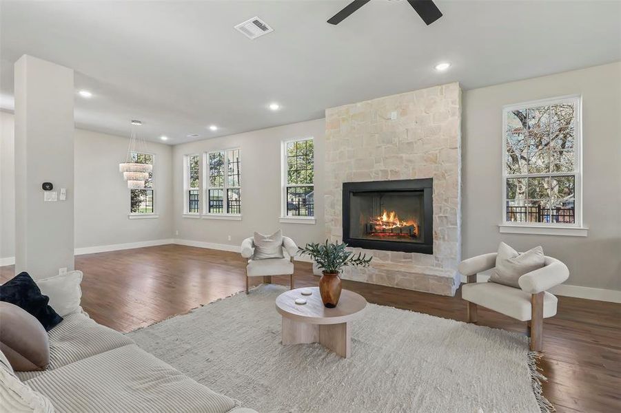Living area with recessed lighting, a stone fireplace, and wood finished floors Living area with recessed lighting, a stone fireplace, and wood finished floors