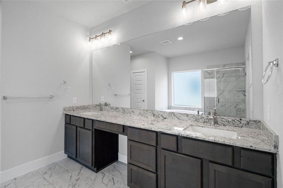 This primary bathroom is definitely move-in ready! Featuring stained cabinets with granite countertops, spacious walk-in closet with shelving, high ceilings, custom paint, sleek and dark modern finishes.