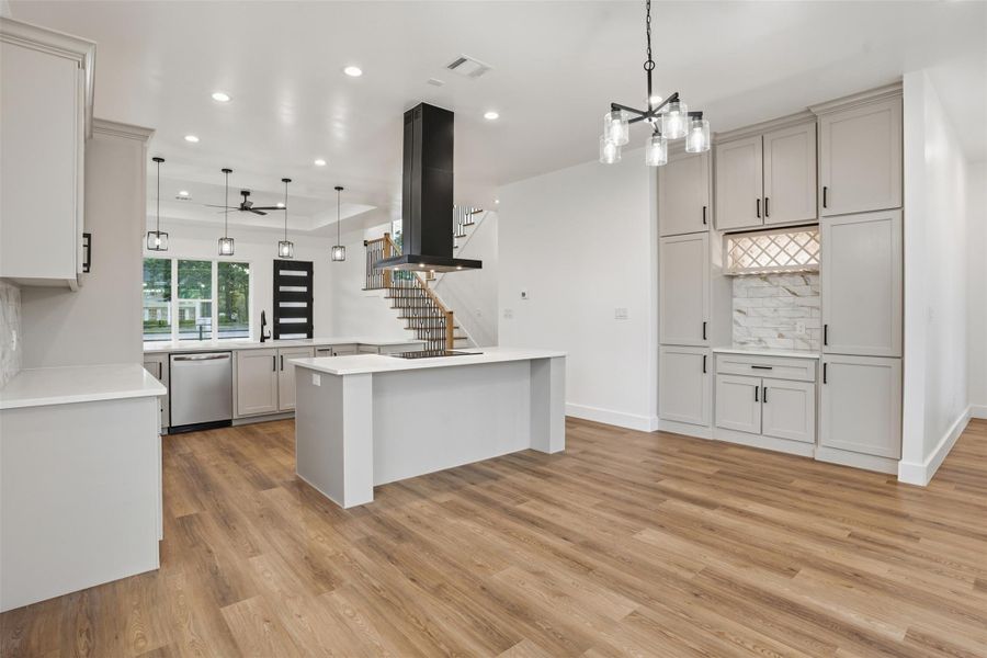 Kitchen with range hood, a kitchen island, pendant lighting, decorative backsplash, and dishwasher