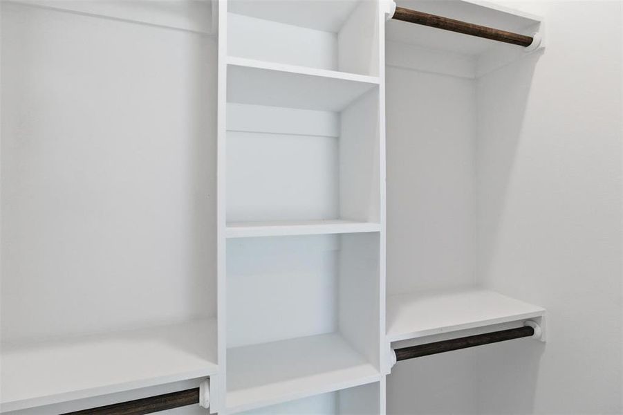 Custom closet system featuring white shelving and dark wood-finish hanging rods