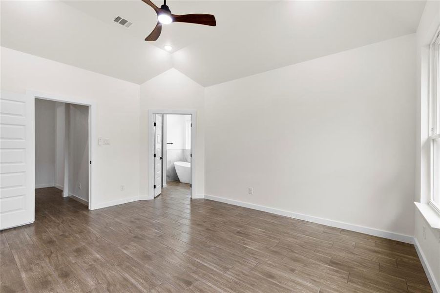 Room featuring vaulted ceilings, wood-finish flooring, and crisp white walls