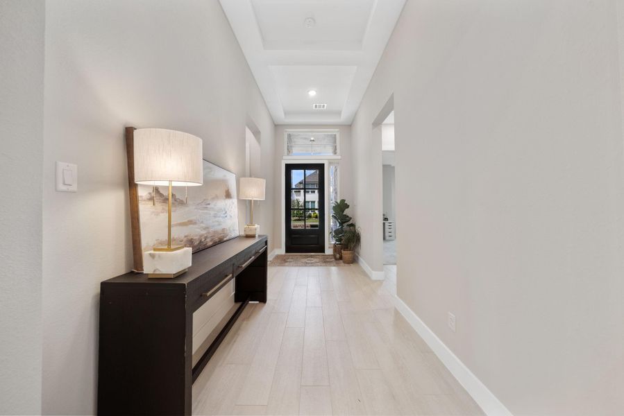 The spacious hallway features high ceilings, elegant lighting, and large, beautiful tiles that lead you toward the front door. The spacious hallway features high ceilings, elegant lighting, and large, beautiful tiles that lead you toward the front door.