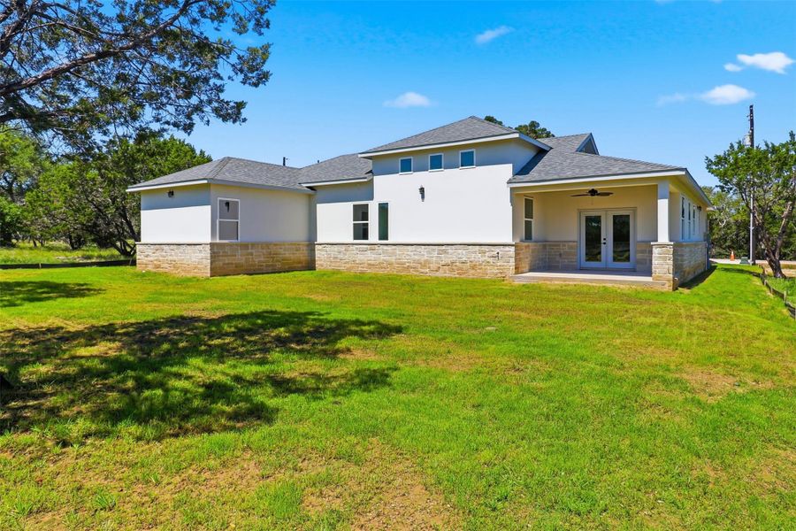 Contemporary exterior featuring a white stucco finish, stone veneer foundation, and a covered back patio with French doors Contemporary exterior featuring a white stucco finish, stone veneer foundation, and a covered back patio with French doors