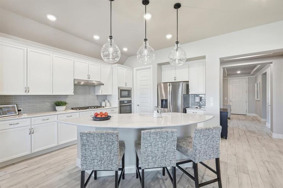 Kitchen with backsplash, a breakfast bar, white cabinets, and recessed lighting