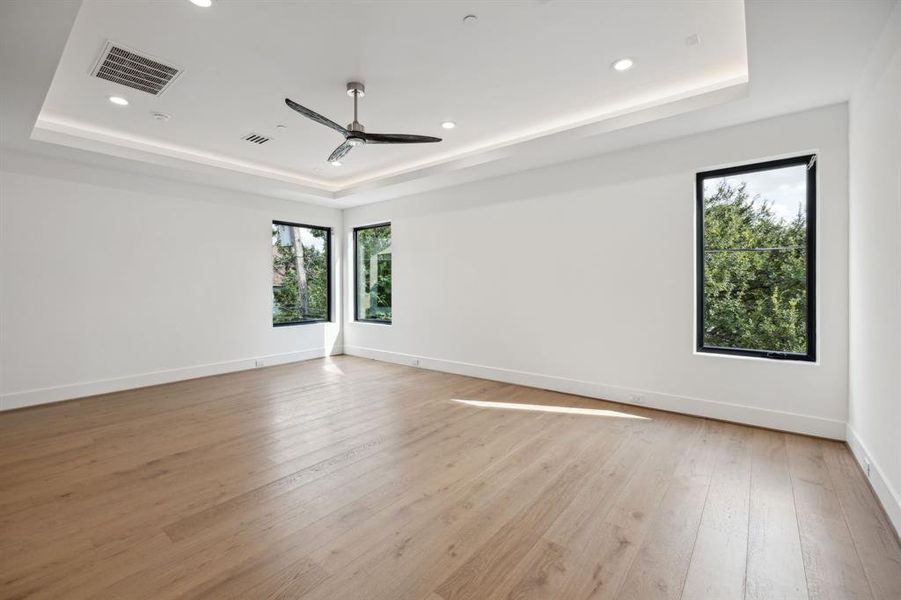 The primary bedroom features a neutral color palette with white walls and engineered solid wood floors, creating a calm atmosphere and relaxing place to unwind.