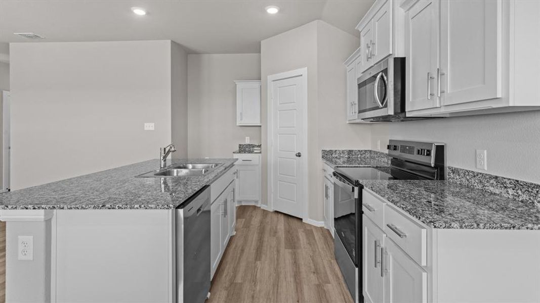 Kitchen featuring stainless steel appliances, a sink, light wood-style flooring, white cabinets, and recessed lighting Kitchen featuring stainless steel appliances, a sink, light wood-style flooring, white cabinets, and recessed lighting