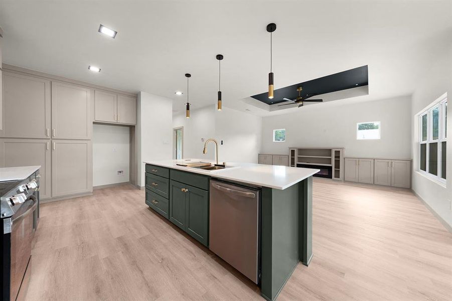 Kitchen featuring dishwasher, light wood-type flooring, light countertops, a sink, and range
