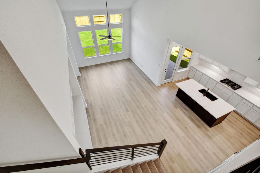 Unfurnished living room with wood finished floors, a towering ceiling, and a ceiling fan