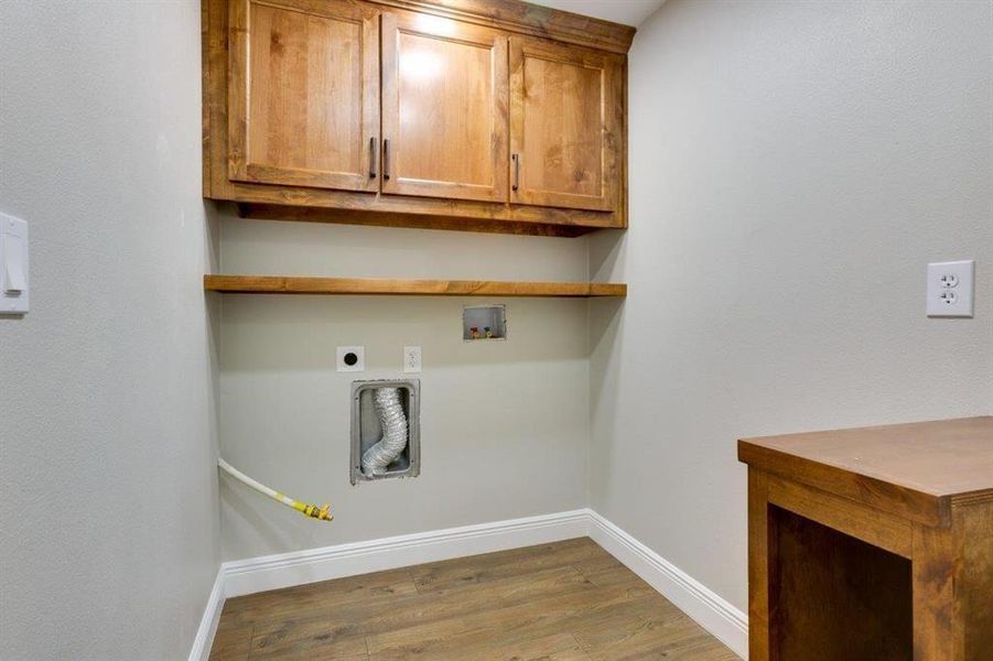 Washroom featuring light wood-style flooring, cabinet space, hookup for a washing machine, and electric dryer hookup