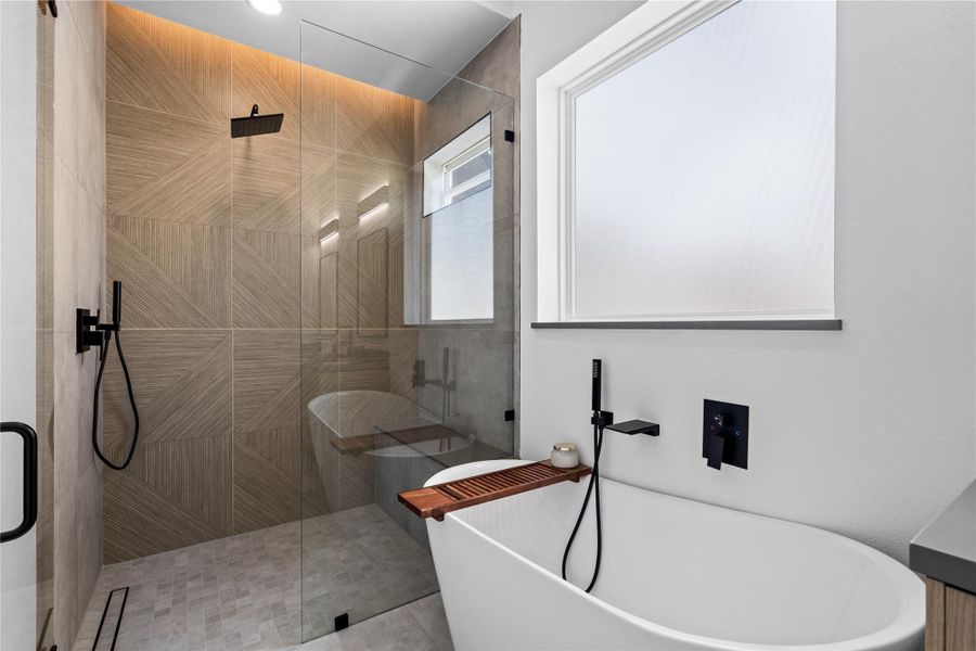 A sanctuary of tactility and light: the frameless glass shower showcases oversized parquet-pattern tile, a linear drain, and a built-in bench, while the sculptural soaking tub rests beneath a privacy-glazed window. Matte-black fittings cut a crisp silhouette—tailored for lingering soaks and restorative rituals at home. A sanctuary of tactility and light: the frameless glass shower showcases oversized parquet-pattern tile, a linear drain, and a built-in bench, while the sculptural soaking tub rests beneath a privacy-glazed window. Matte-black fittings cut a crisp silhouette—tailored for lingering soaks and restorative rituals at home.