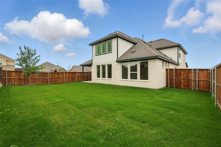 Back of property featuring a shingled roof and brick siding Back of property featuring a shingled roof and brick siding
