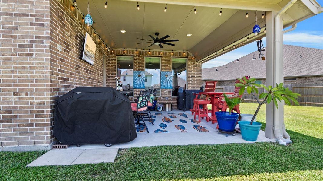 Enjoy outdoor living under this inviting covered patio, featuring generous space for seating, an oversized ceiling fan, and a dedicated grilling area—perfect for relaxing and entertaining. Enjoy outdoor living under this inviting covered patio, featuring generous space for seating, an oversized ceiling fan, and a dedicated grilling area—perfect for relaxing and entertaining.